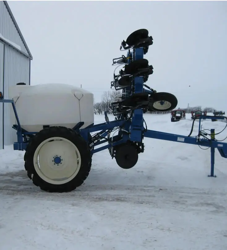 A blue and white tractor with a plow attached to it.